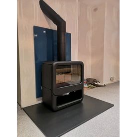 Dovre Rock sitting on a honed granite hearth. A vlaze heat shield mounted on the wall behind. 
